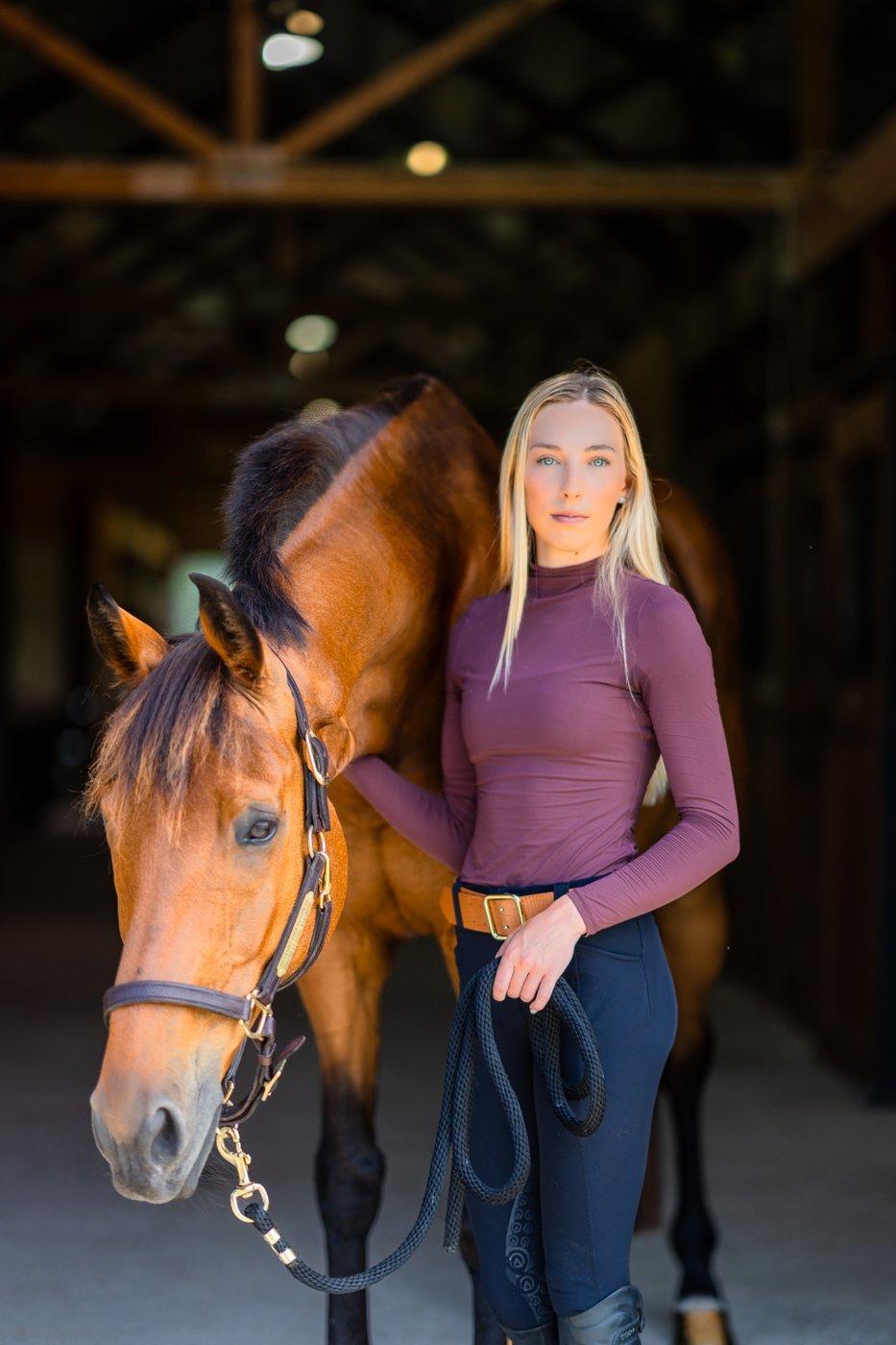 Lara with her bay horse in the barn aisle